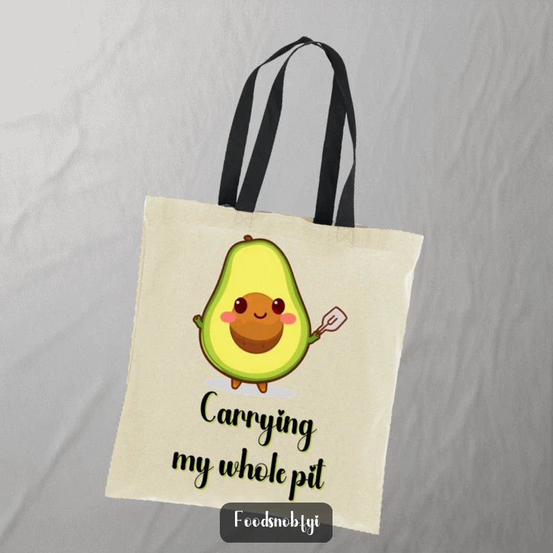 Funny tote bag showcasing a smiling avocado character balancing its pit on a tiny spatula, perfect for carrying essentials.